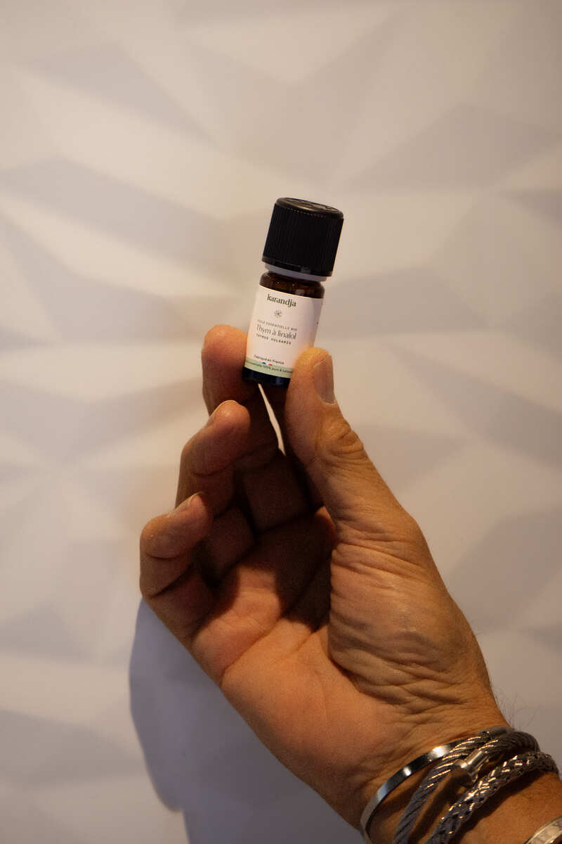 une main qui tient un flacon d'huile essentielle de thym à linalol Bio