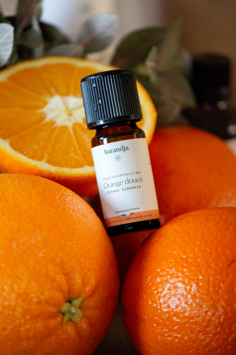 un flacon d'huile essentielle d'orange douce posé devant une rondelle d'orange