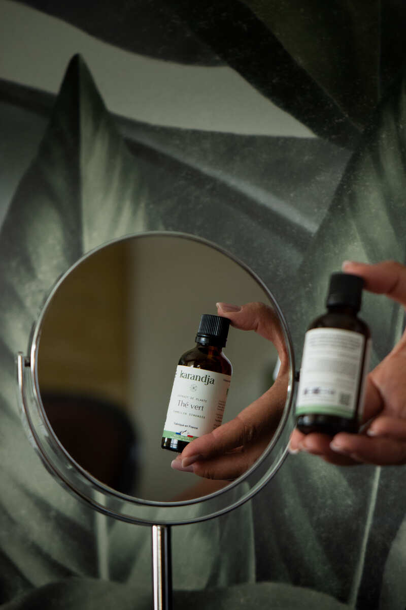 flacon d'extrait de plante de thé vert devant un miroir Karandja